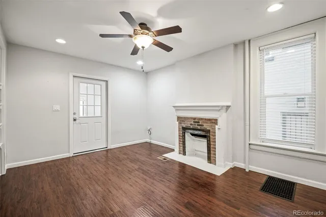 an empty room with wooden floor fireplace and windows
