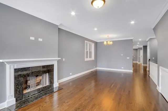 an empty room with wooden floor a fireplace and windows