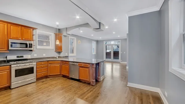 a large kitchen with stainless steel appliances granite countertop a stove and a wooden floors