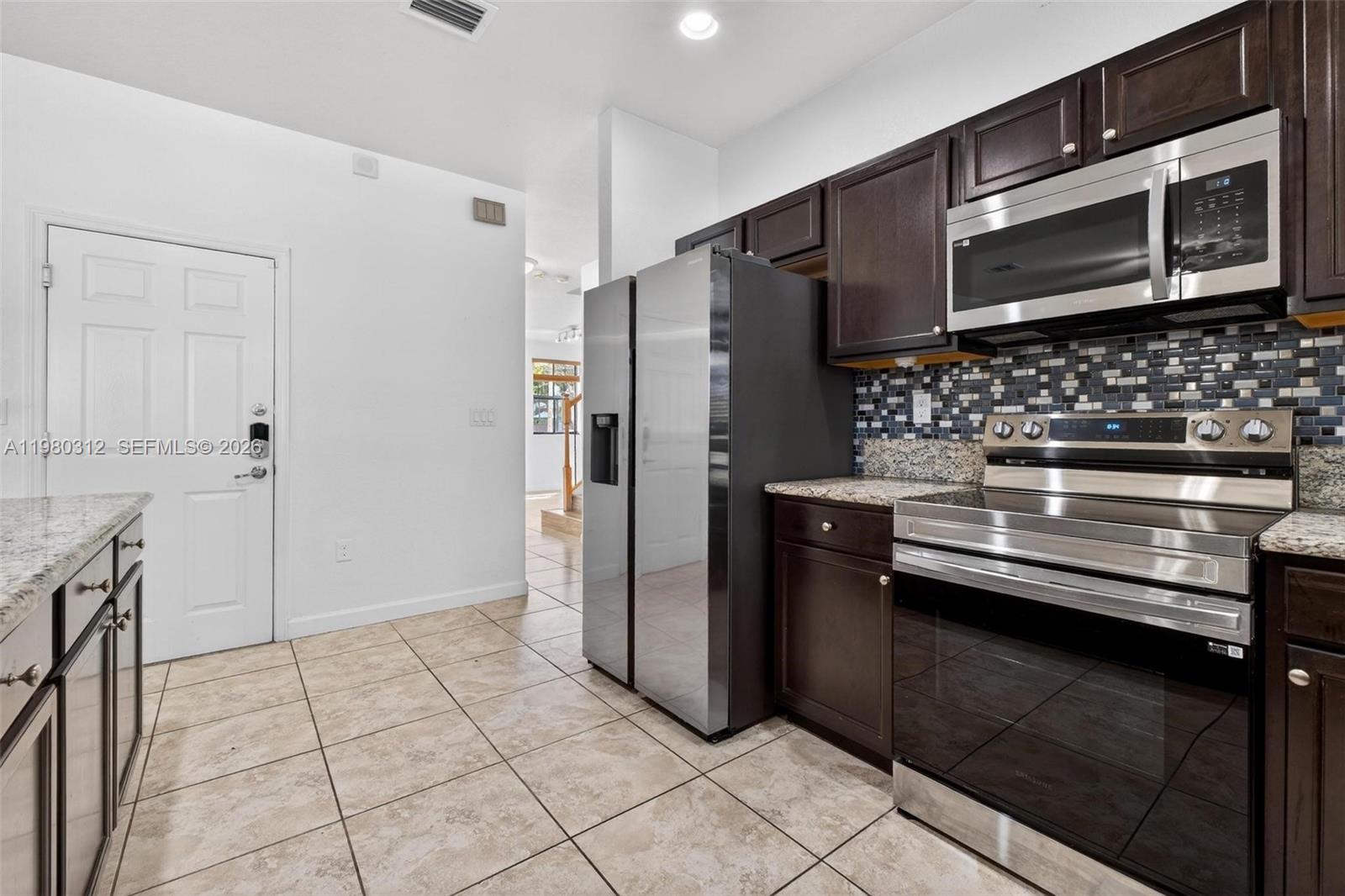 11561 Southwest 232nd Lane, Unit 11561 Homestead, FL 33032 - Photo 15 of 61 a kitchen with stainless steel appliances granite countertop a refrigerator and a stove top oven