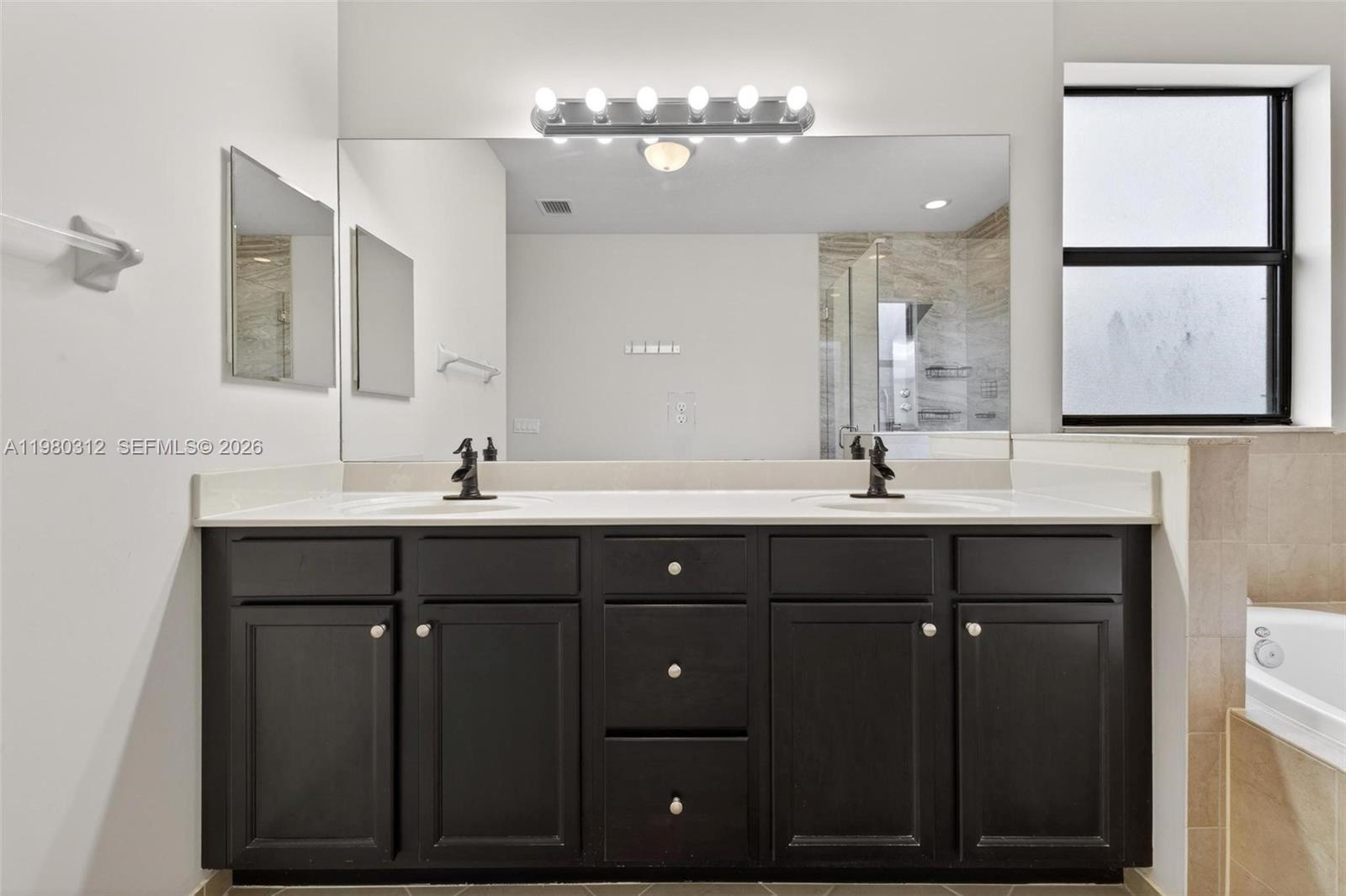 11561 Southwest 232nd Lane, Unit 11561 Homestead, FL 33032 - Photo 35 of 61 a bathroom with a double vanity sink a mirror a lamp and a bathtub