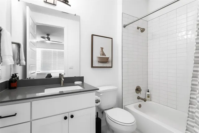 a bathroom with a granite countertop sink a toilet a mirror and shower