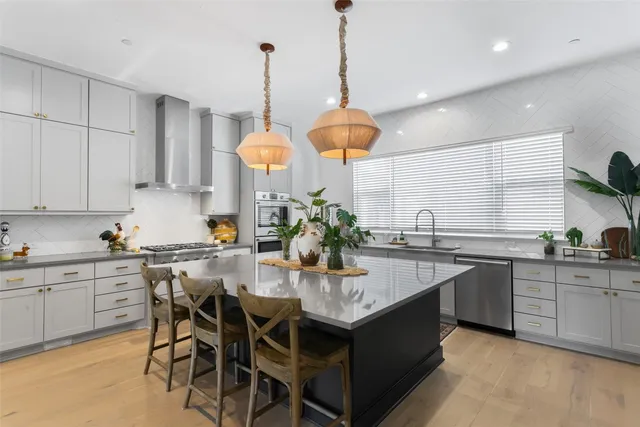 a kitchen with stainless steel appliances granite countertop a sink a stove and chairs