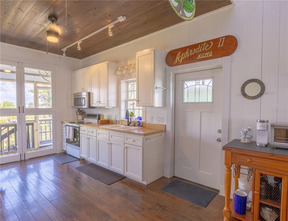 8796 Grand Avenue Boca Grande, FL 33921 - Photo 12 of 19 a open kitchen with stainless steel appliances granite countertop a refrigerator a sink dishwasher a stove and white countertops with wooden floor