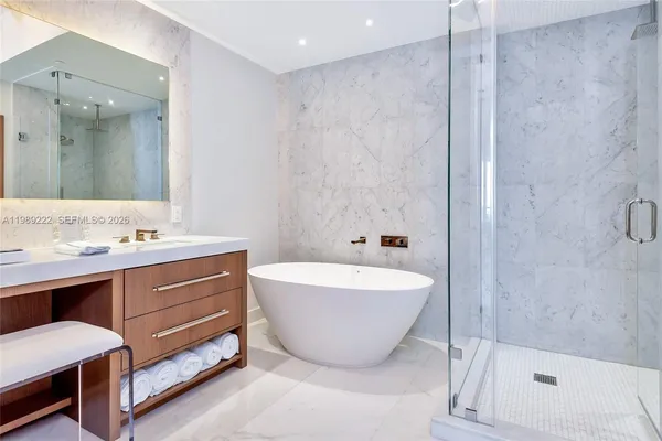 a spacious bathroom with a tub sink shower and mirror