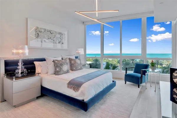 a spacious bedroom with a bed a couch and a chandelier