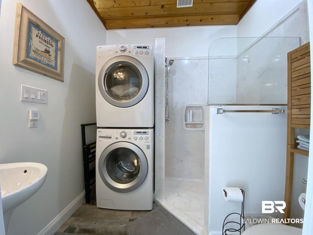 28888 Canal Road, Unit 77 Orange Beach, AL 36561 - Photo 9 of 23 Compact bathroom featuring a wood-panel ceiling, pedestal sink, and a stacked washer and dryer unit