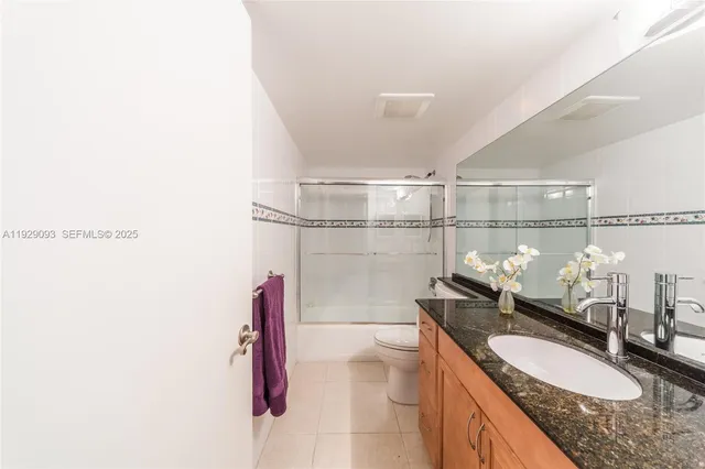 a bathroom with a granite countertop sink a toilet and shower