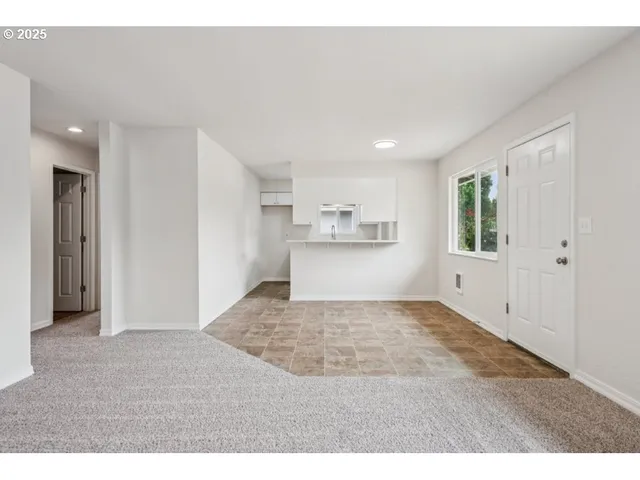 a view of an empty room and kitchen