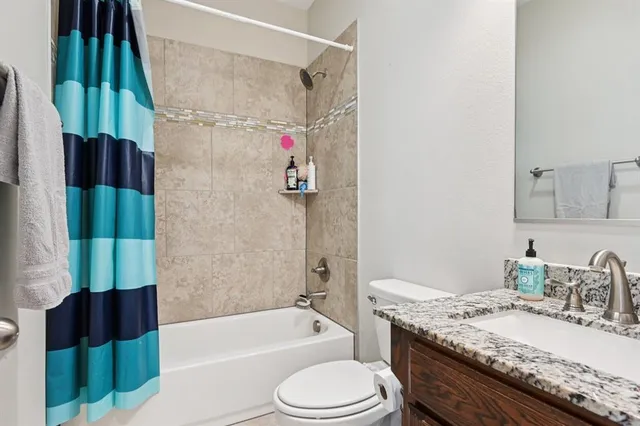 a bathroom with a granite countertop bathtub sink vanity mirror and toilet