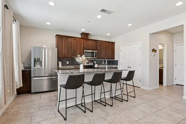 a kitchen with stainless steel appliances granite countertop a refrigerator and a stove top oven