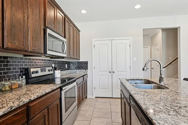 a kitchen with stainless steel appliances granite countertop a sink stove and cabinets