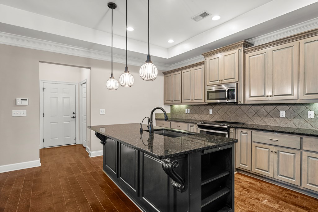 8848 Promenade Place Midland, GA 31820 - Photo 4 of 21 a kitchen with kitchen island granite countertop a sink a stove and wooden cabinets