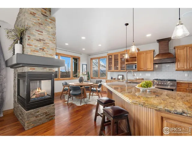 a kitchen with stainless steel appliances granite countertop a stove refrigerator a dining table and chairs with the wooden floor