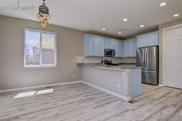 a kitchen with granite countertop a refrigerator and a stove top oven