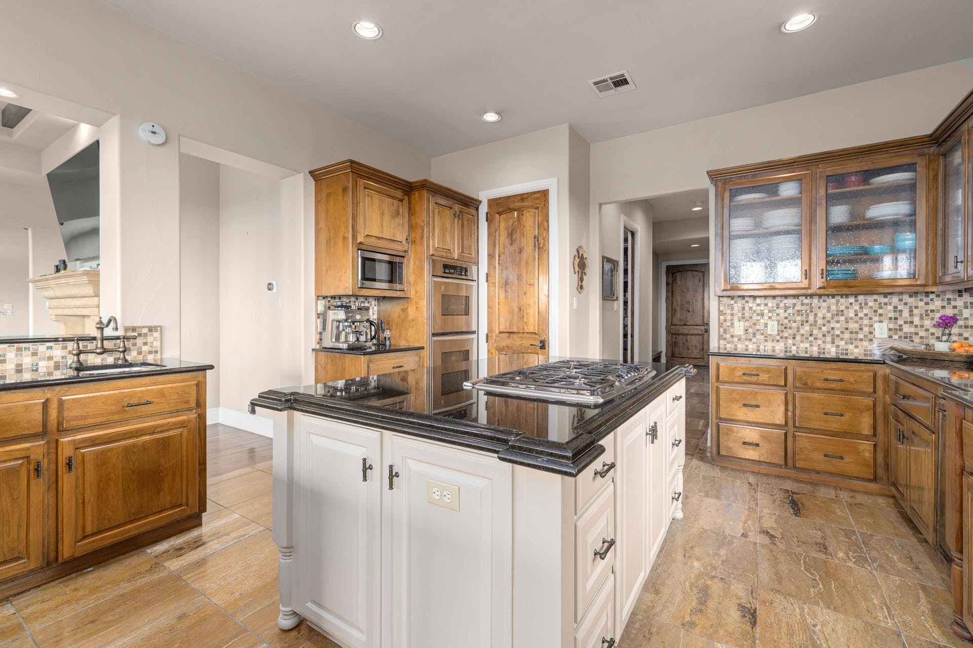 9104 Atwater Cove Austin, TX 78733 - Photo 8 of 36 Kitchen with brown cabinetry, white cabinets, backsplash, and recessed lighting