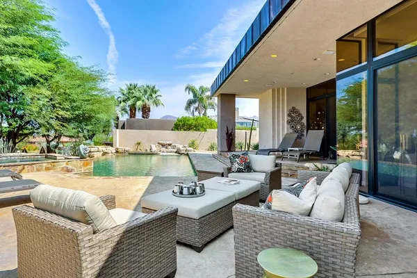 a view of a swimming pool and lounge chairs in the patio