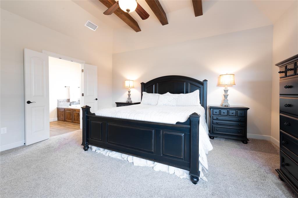 266 Weatherby Street Tuscola, TX 79562 - Photo 12 of 29 Bedroom with light carpet, ceiling fan, lofted ceiling with beams, and ensuite bath