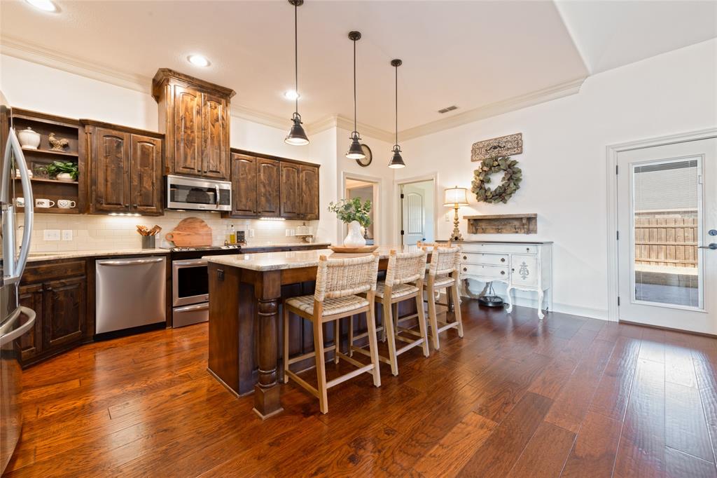 266 Weatherby Street Tuscola, TX 79562 - Photo 8 of 29 Kitchen featuring dark wood finish cabinets, hanging light fixtures, stainless steel appliances, a breakfast bar area, and open shelves