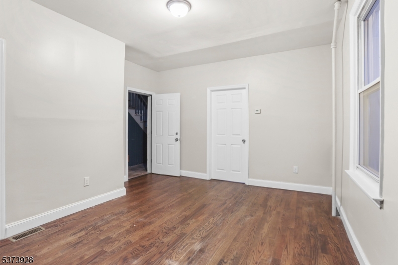 79 Irving Street Newark, NJ 07104 - Photo 9 of 30 an empty room with wooden floor and windows