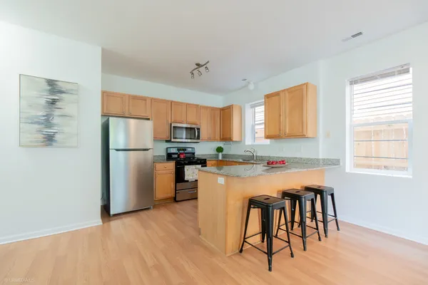 a kitchen with stainless steel appliances a refrigerator a stove a dining table and chairs
