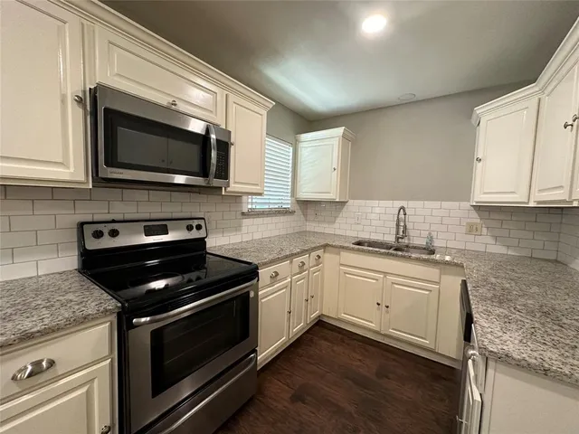 a kitchen with granite countertop a sink and steel appliances