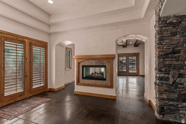 2464 East Granite Way St. George, UT 84790 - Photo 41 of 106 Unfurnished dining room with french doors, arched walkways, a raised ceiling, and a multi sided fireplace