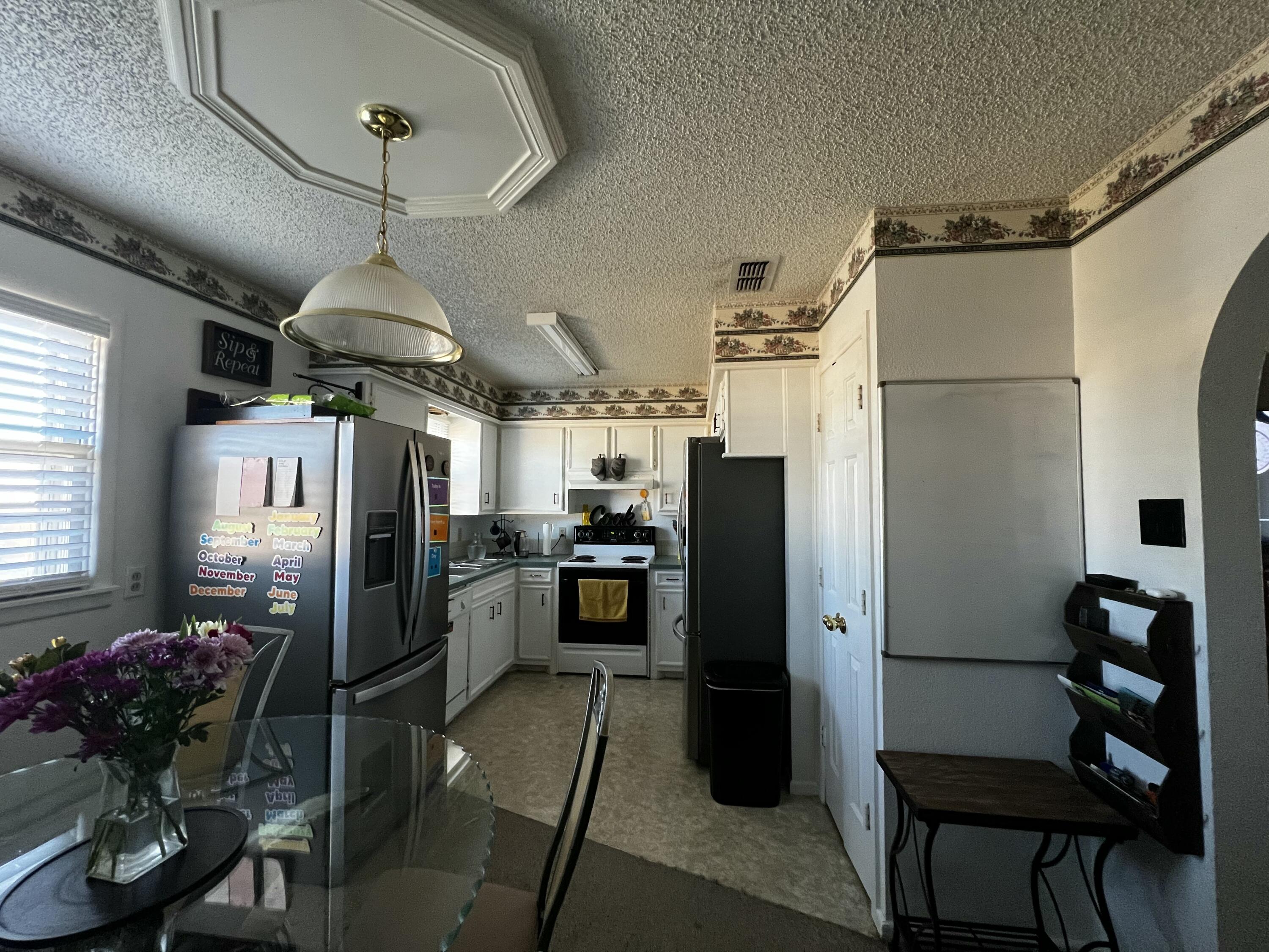 4520 36th Street Lubbock, TX 79414 - Photo 5 of 30 a kitchen with refrigerator a microwave a dining table and chairs
