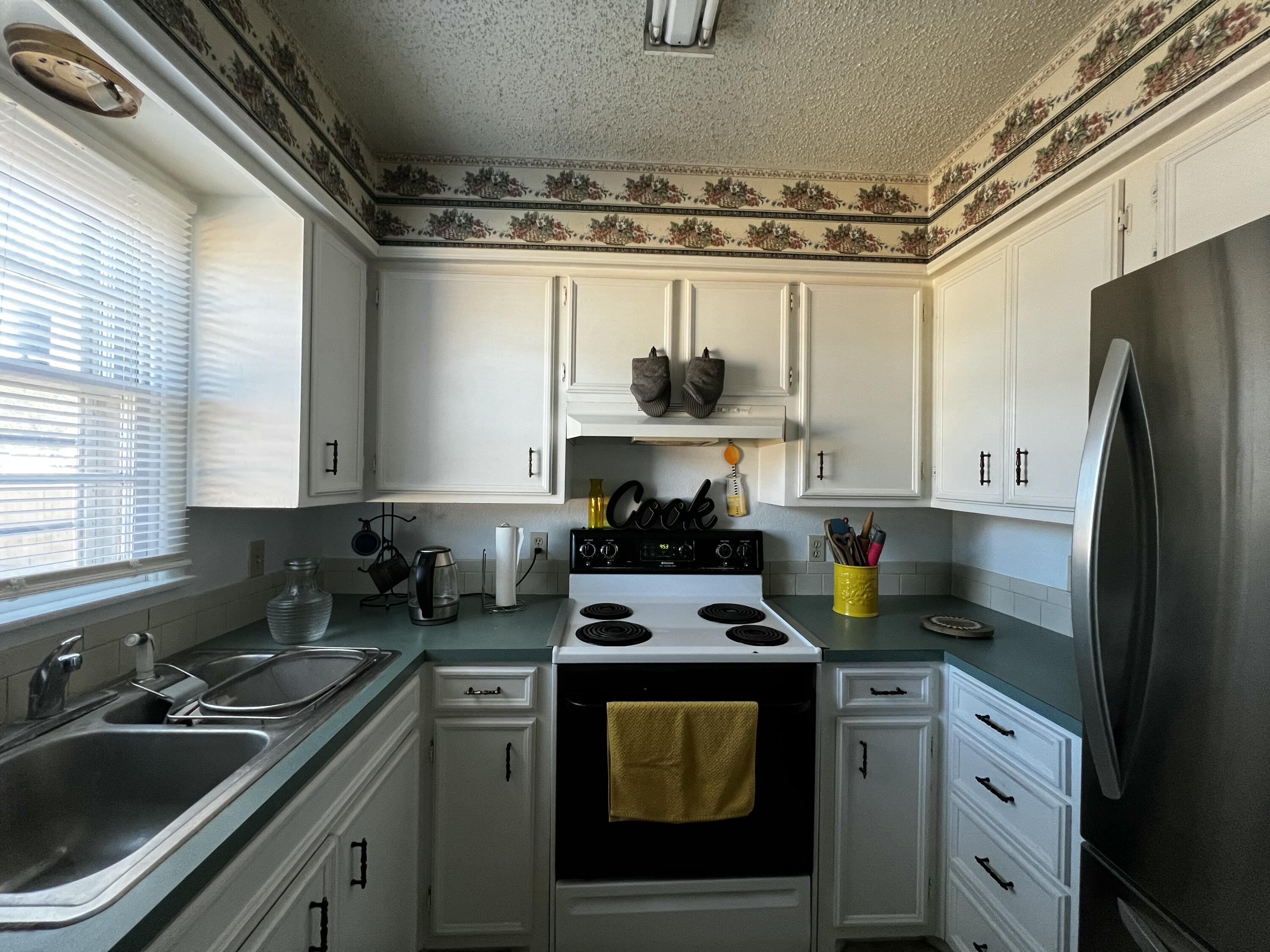 4520 36th Street Lubbock, TX 79414 - Photo 6 of 30 a kitchen with a sink a stove cabinets and refrigerator