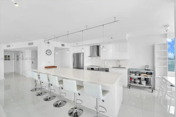a kitchen with stainless steel appliances a refrigerator a sink a stove and white cabinets