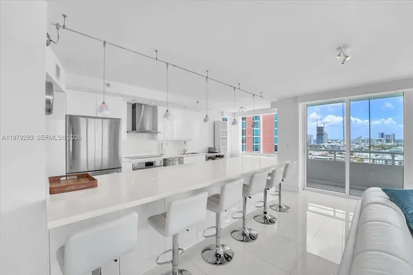 a kitchen with stainless steel appliances a refrigerator a sink a stove and white cabinets
