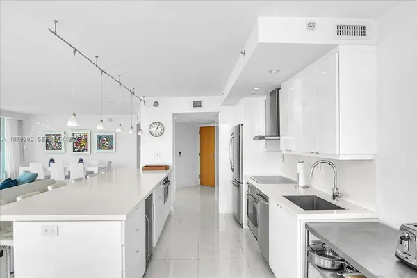 a large white room with kitchen view and large windows