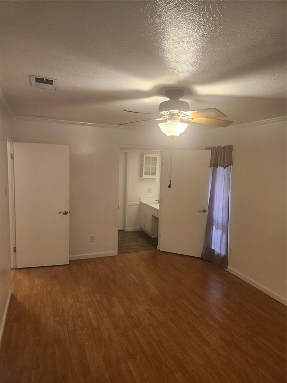 12911 Mitchwin Road Farmers Branch, TX 75234 - Photo 24 of 38 Unfurnished bedroom featuring visible vents, baseboards, a textured ceiling, and wood finished floors