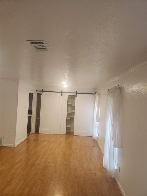 12911 Mitchwin Road Farmers Branch, TX 75234 - Photo 8 of 38 Unfurnished room with a barn door, a textured ceiling, visible vents, and light wood finished floors