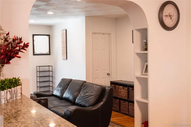 a living room with furniture a wall clock and a potted plant