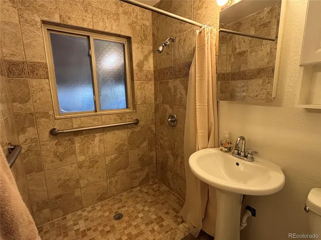a bathroom with a sink shower and a mirror