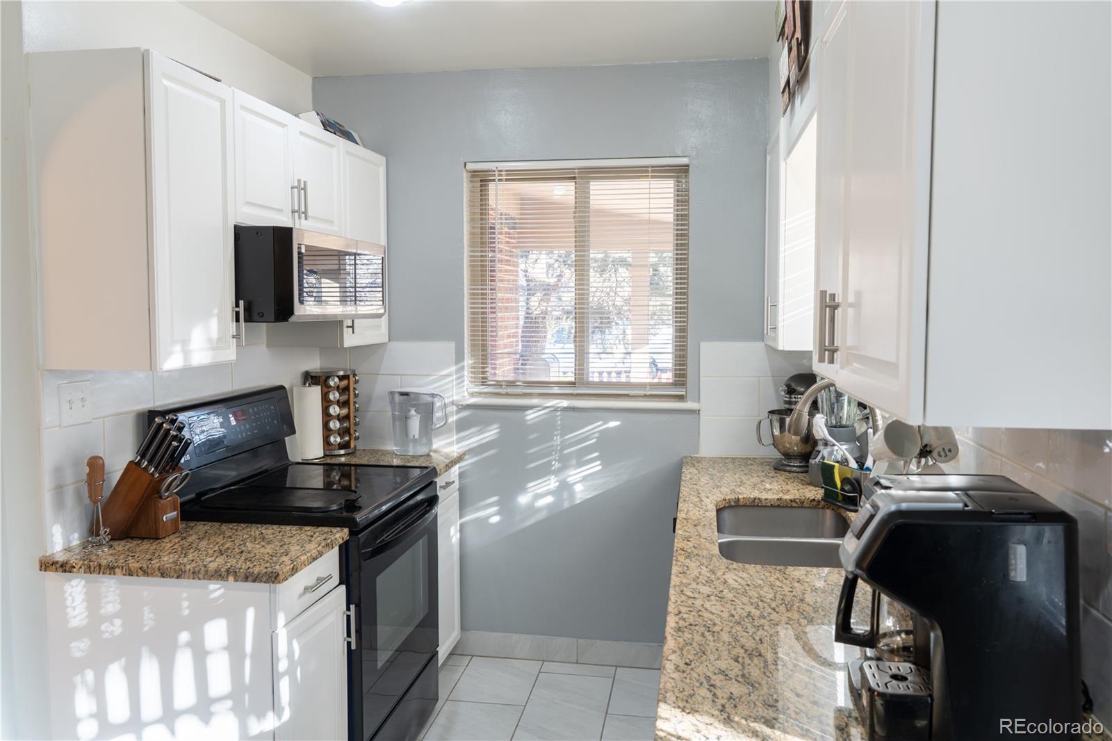 695 South Bryant Street Denver, CO 80219 - Photo 7 of 28 a kitchen with granite countertop a sink a stove and a microwave