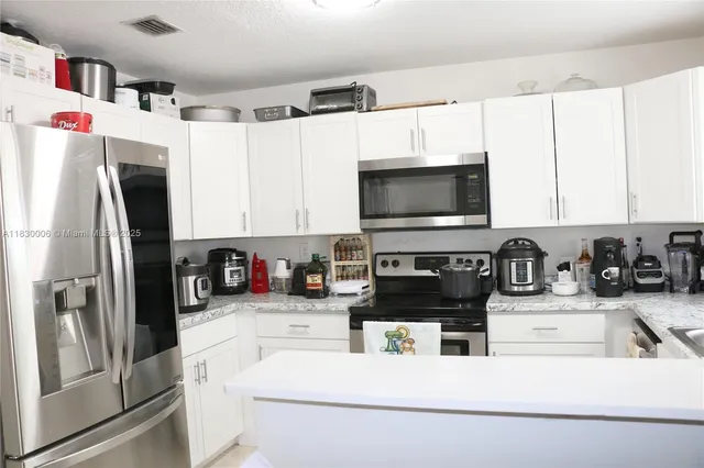 a kitchen with stainless steel appliances a refrigerator sink and white cabinets