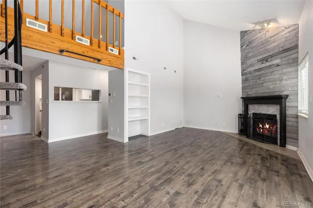 a view of an empty room with wooden floor and a fireplace