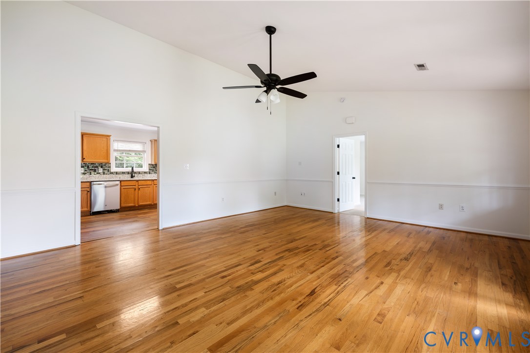 5 Walters Way Bumpass, VA 23024 - Photo 6 of 28 an empty room with wooden floor a ceiling fan and kitchen view