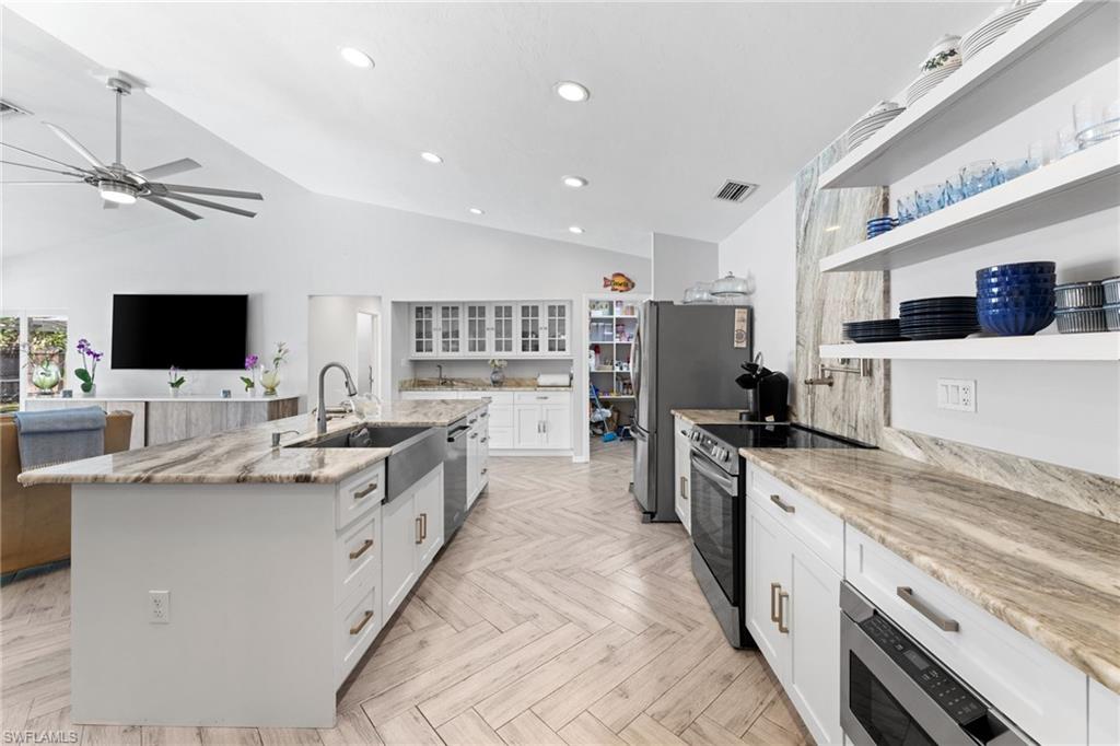 2467 Pinewoods Circle, Unit 3 Naples, FL 34105 - Photo 12 of 33 Kitchen featuring a center island with sink, sink, stainless steel appliances, white cabinets, and light parquet floors