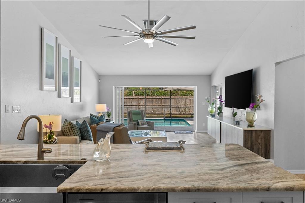2467 Pinewoods Circle, Unit 3 Naples, FL 34105 - Photo 13 of 33 Kitchen with sink, vaulted ceiling, light stone countertops, and ceiling fan