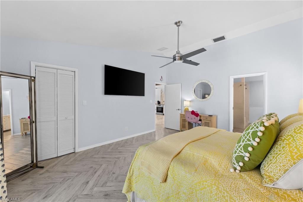 2467 Pinewoods Circle, Unit 3 Naples, FL 34105 - Photo 28 of 33 Bedroom with connected bathroom, a closet, light parquet flooring, ceiling fan, and high vaulted ceiling