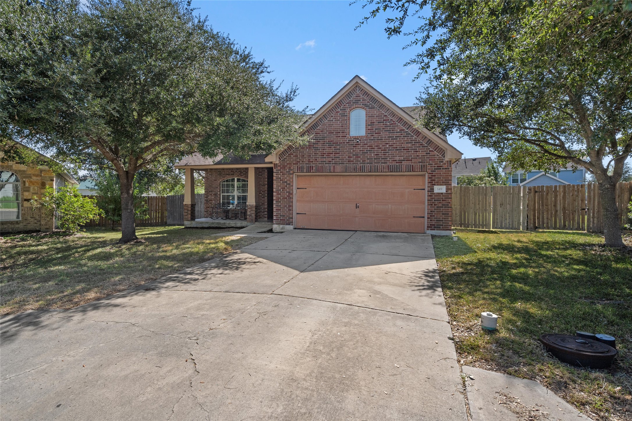 149 Dropper Kyle, TX 78640 - Photo 9 of 33 Established shade trees frame the classic brick exterior and concrete driveway of this suburban home.