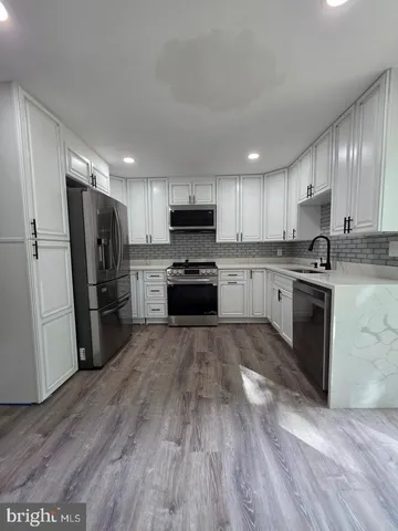 a kitchen with granite countertop a refrigerator stove top oven and sink