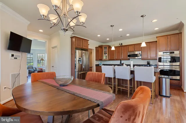 a living room with stainless steel appliances furniture a flat screen tv and kitchen view