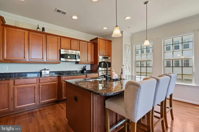 a kitchen with granite countertop wooden cabinets dining table and stainless steel appliances