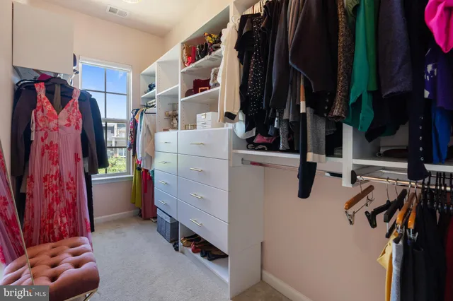 a view of walk in closet with clothes and shoes