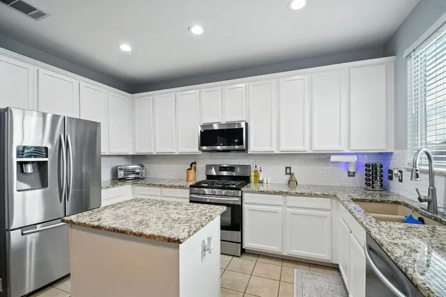a kitchen with granite countertop a sink stainless steel appliances and white cabinets