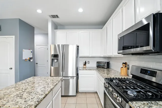 a kitchen with stainless steel appliances kitchen island granite countertop a refrigerator stove and microwave